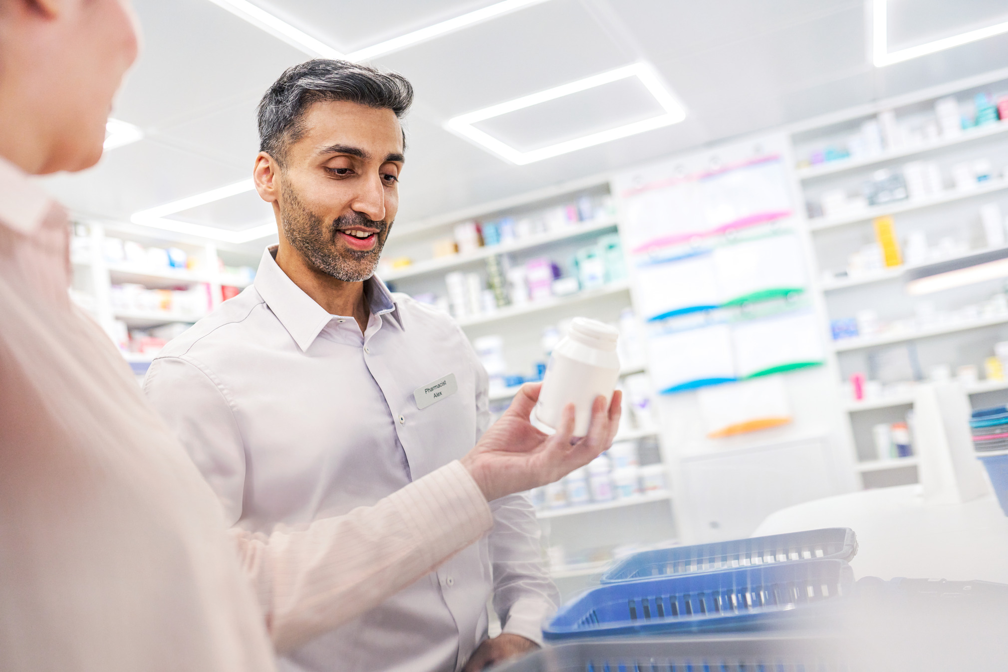 Pharmacists in conversation while holding a pharmaceutical product.